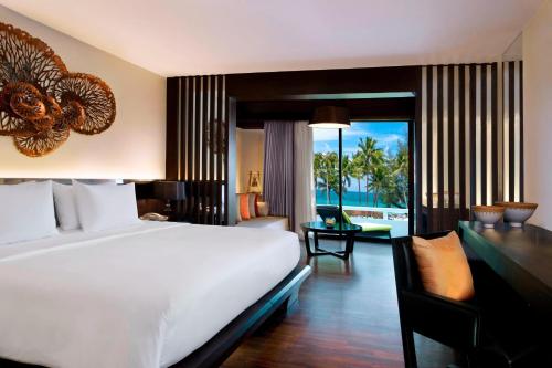 a bedroom with a large white bed and a desk with a view at Le Meridien Phuket Beach Resort in Karon Beach