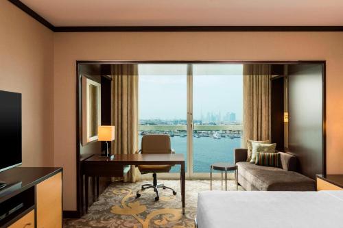 a hotel room with a desk and a room with a view at Sheraton Dubai Creek Hotel & Towers in Dubai