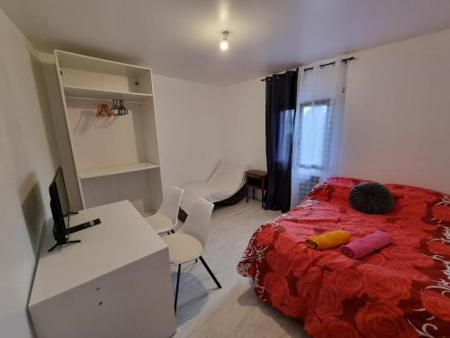 1 dormitorio con cama roja y escritorio con ordenador en Chambre cosy, en Persan