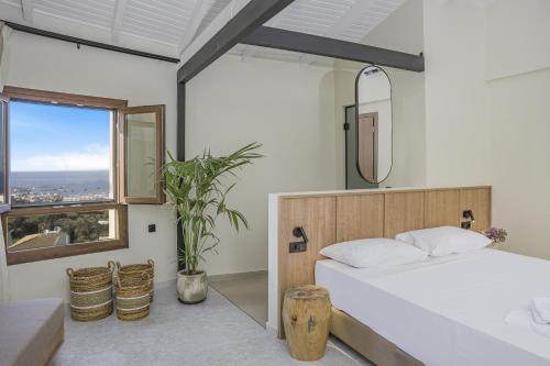 a bedroom with a white bed and a large window at Achatis Suites in Hersonissos