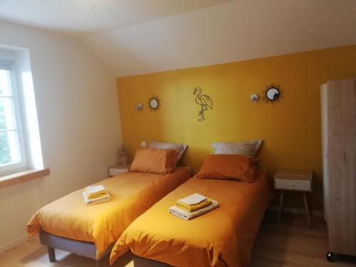 Duas camas individuais num quarto com paredes amarelas. em Gîte garde-barrière 2 chambres em Saint-Guen