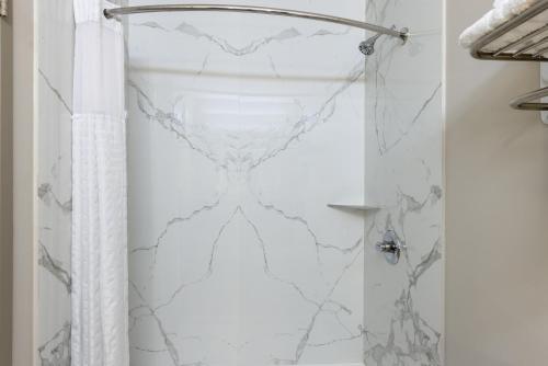 a shower with a white marble shower curtain at Days Inn & Suites by Wyndham Fort Bragg/Cross Creek Mall in Fayetteville
