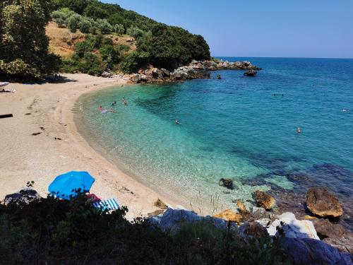 a beach with a blue umbrella and people in the water at Sotiria Apartments in Kókkinon Nerón