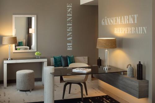 a living room with a table and chairs and a mirror at Renaissance Hamburg Hotel in Hamburg