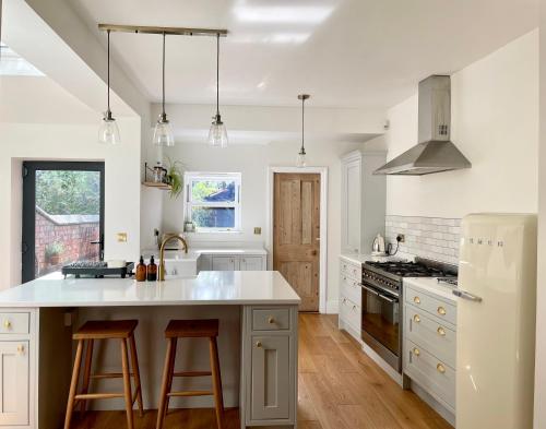 a kitchen with white cabinets and a white refrigerator at The Harborne Home opposite QE hospital & Birmingham university in Birmingham