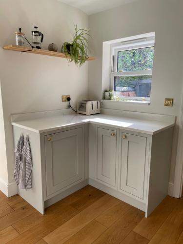 a kitchen with white cabinets and a window at The Harborne Home opposite QE hospital & Birmingham university in Birmingham