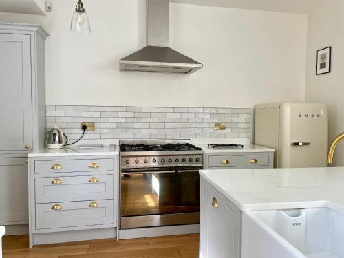 a white kitchen with a stove and a refrigerator at The Harborne Home opposite QE hospital & Birmingham university in Birmingham