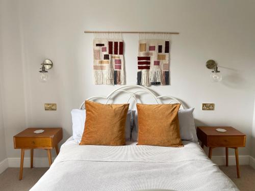 a bedroom with a white bed with pillows and two tables at The Harborne Home opposite QE hospital & Birmingham university in Birmingham