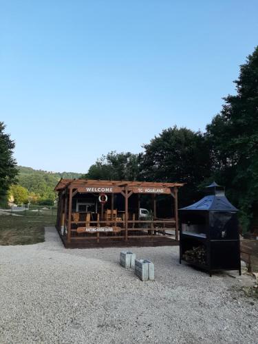 a wooden pavilion with a black roof and a building at Camp Aqualand in Bihać