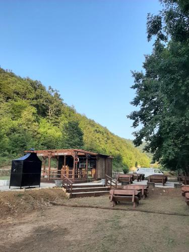 a wooden building with picnic tables in front of a hill at Camp Aqualand in Bihać