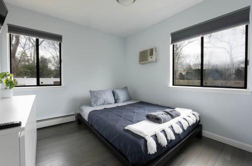 a bedroom with a large bed with two windows at Nature's Haven in the Hamptons in East Hampton