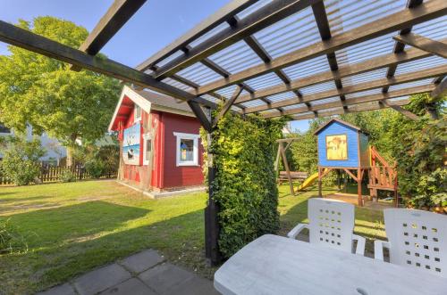 una mesa de picnic bajo una pérgola con una casa de juegos en Zinnowitz, Haus Jörn, en Zinnowitz