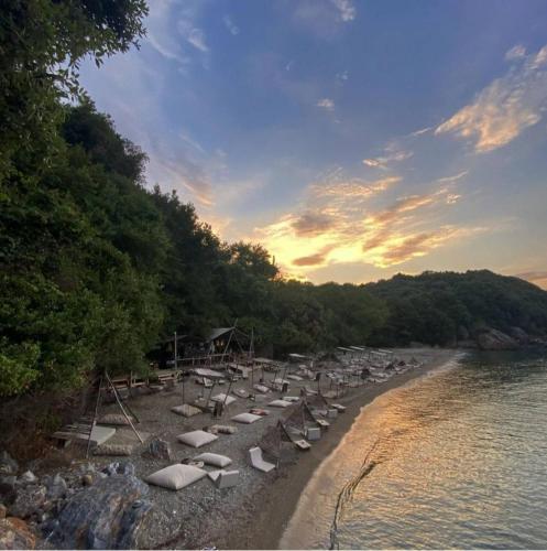 a beach with chairs and umbrellas on the shore at Sotiria Apartments in Kókkinon Nerón