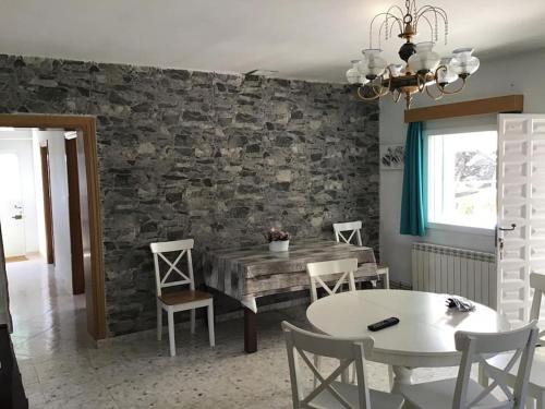 a dining room with a table and chairs and a stone wall at Numancia 12 in Santa María de la Alameda