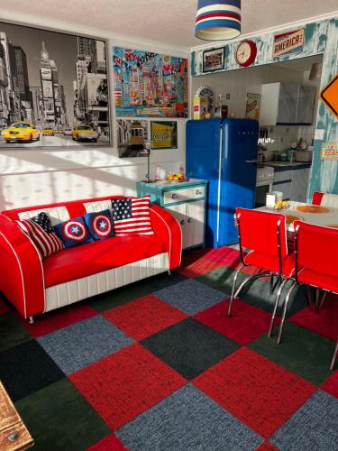 a living room with a red couch and a kitchen at American Retro Chalet in Hemsby