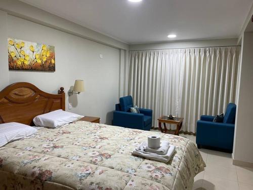 ein Schlafzimmer mit einem Bett und zwei blauen Stühlen in der Unterkunft Hermoso minidepartamento in Huaraz