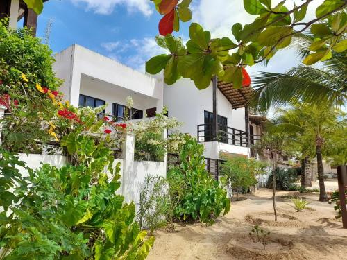 a white building with plants in front of it at Agapanthus Apartamentos in Jericoacoara