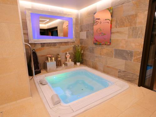 un bagno con vasca idromassaggio e specchio di Chambre d'hôtes & SPA Mas Dels Esquirols a Saint-André