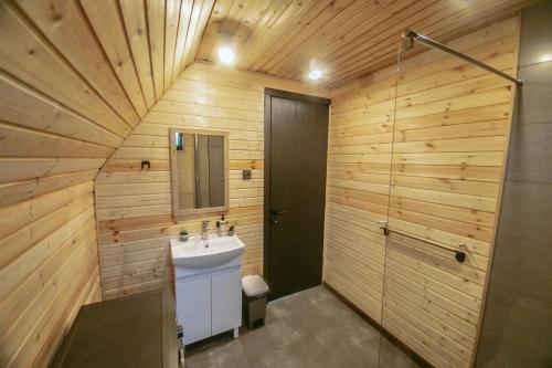 a bathroom with wooden walls and a sink and a shower at Shaori Lake Cottages in Kharistʼvala
