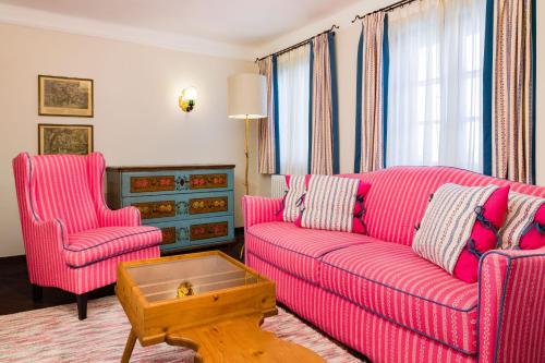 a living room with a pink couch and two chairs at Hotel Goldener Hirsch, A Luxury Collection Hotel, Salzburg in Salzburg