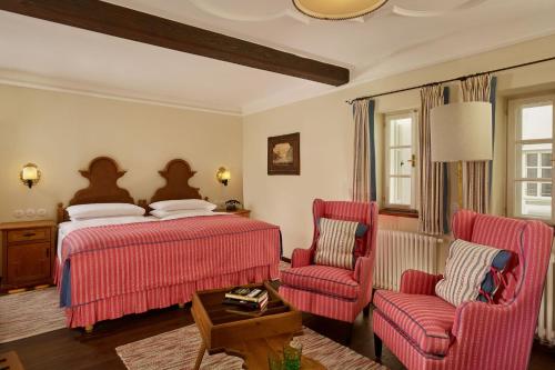 a bedroom with a bed and two chairs at Hotel Goldener Hirsch, A Luxury Collection Hotel, Salzburg in Salzburg