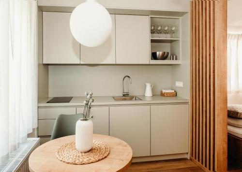 uma cozinha com armários brancos e uma mesa com um vaso em Apartments Triglav em Mojstrana