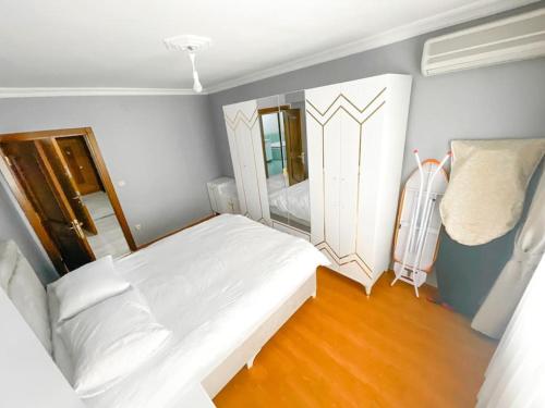 a small bedroom with a white bed and a mirror at A family apartment in a quiet area in Istanbul