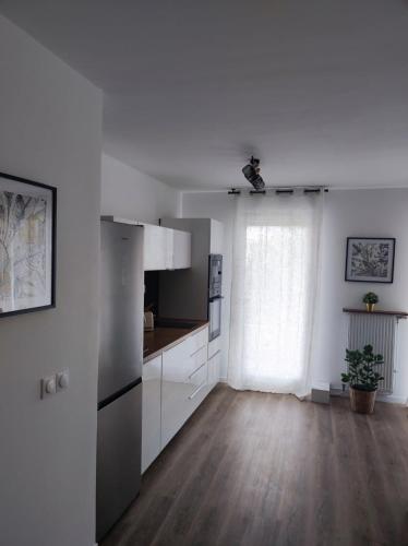 une cuisine avec des armoires blanches et un plancher en bois dans l'établissement Proche de Paris T3 tout confort, Évry-Courcouronnes