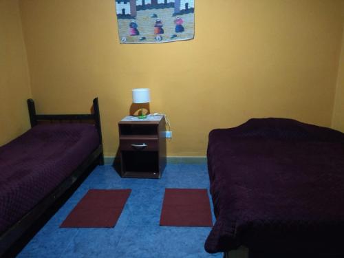 1 dormitorio con 2 camas y mesita de noche con lámpara en Hosteria M.G en Tilcara