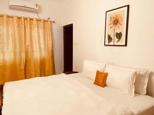 a bedroom with a white bed with a yellow curtain at Fortis Rooms in Cochin