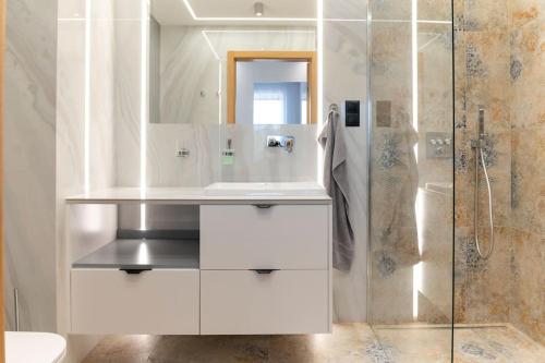 uma casa de banho branca com um lavatório e um chuveiro em Apartament Koral - Kompozytorów Polskich 7 em Lublin