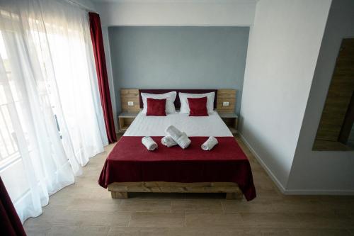 a bedroom with a bed with red sheets and pillows at ADAMZ in Vama Veche