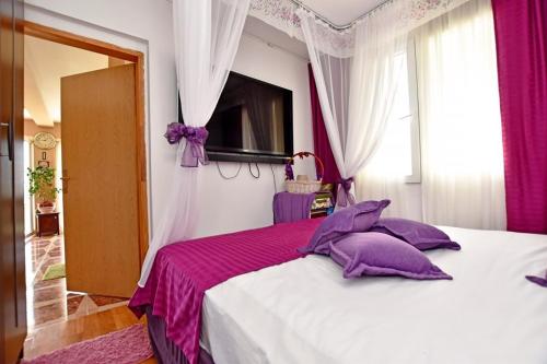 1 dormitorio con 1 cama grande con almohadas moradas en Vila Djordjevic, en Herceg-Novi