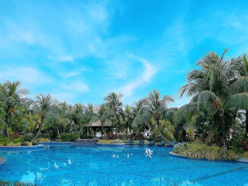 a resort swimming pool with palm trees in the background at Forest city 2bedroom homestay in Johor Bahru