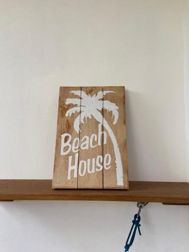 a wooden shelf with a beach house sign on it at Otium in Coteau Raffin
