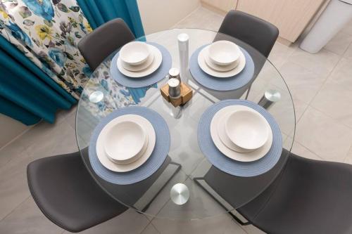 a glass table with blue and white hats on it at Osmax Oasis, 2 BD and 2 BA, Gated, near Puerto Seco Beach in Discovery Bay