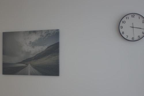 a clock on a wall next to a picture of a road at Studio Paris Sud à côté du métro in Villejuif