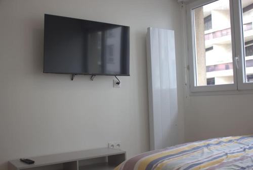um quarto com uma televisão de ecrã plano na parede em Studio Paris Sud à côté du métro em Villejuif