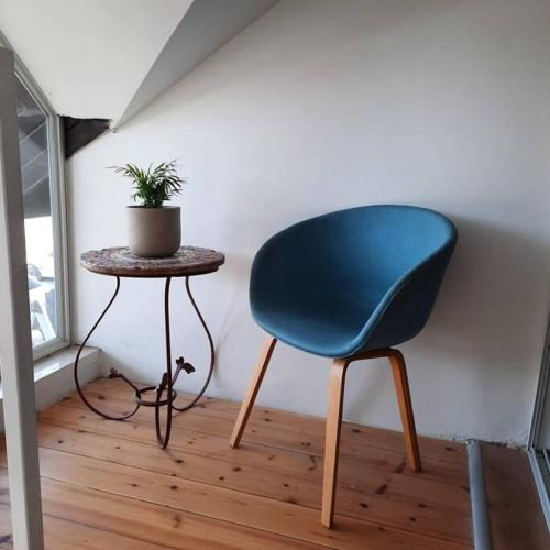 una silla azul junto a una mesa con una maceta en ירוק בגולן, en Katzrin