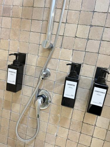 prysznic z 3 dozownikami mydła na podłodze wyłożonej kafelkami w obiekcie Bonne Nuit Terracina w mieście Terracina