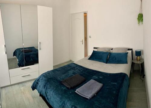 Schlafzimmer mit einem Bett mit blauer Bettwäsche und einem Spiegel in der Unterkunft Agréable appartement 2 pieces a forbach avec Garage fermé - check in autonome in Forbach