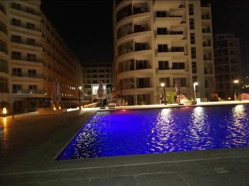 a swimming pool in front of some buildings at night at Scandic Resort Hurghada in Hurghada