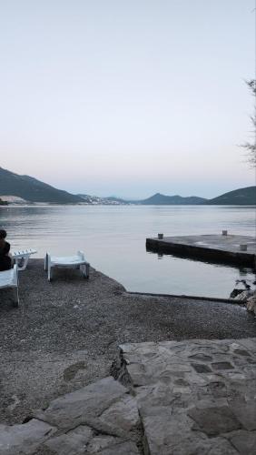 a person sitting on a bench next to a body of water at Apartman PITOSPORA in Klek