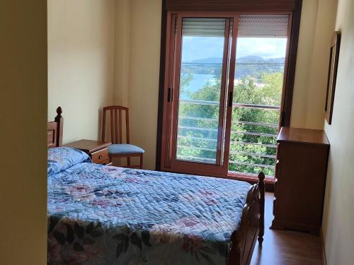 a bedroom with a bed and a large window at A pe de praia in Bueu