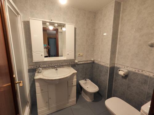 a bathroom with a sink and a toilet and a mirror at A pe de praia in Bueu