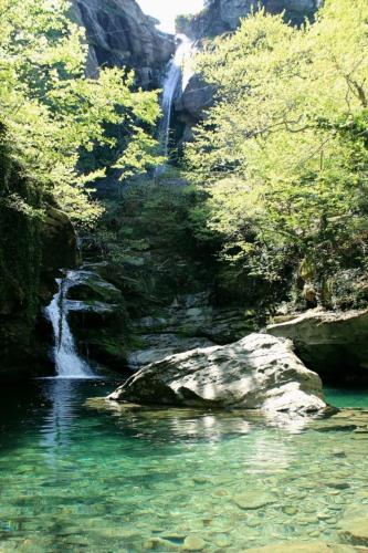 a waterfall in the middle of a river with trees at Sotiria Apartments in Kókkinon Nerón