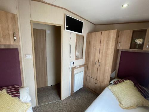 a bedroom with two beds and a tv on the wall at Lakeside Retreat 1 with hot tub, private fishing peg situated at Tattershall Lakes Country Park in Tattershall