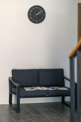 a black couch with a clock on a wall at ADAMZ in Vama Veche