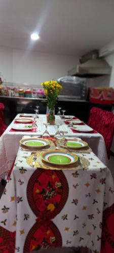 een lange tafel met borden en een vaas met bloemen erop bij Refugio de la felicidad in Huancayo