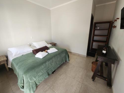 a bedroom with a bed with two pillows and a table at Pousada Luz de Candeia in São João Batista do Glória